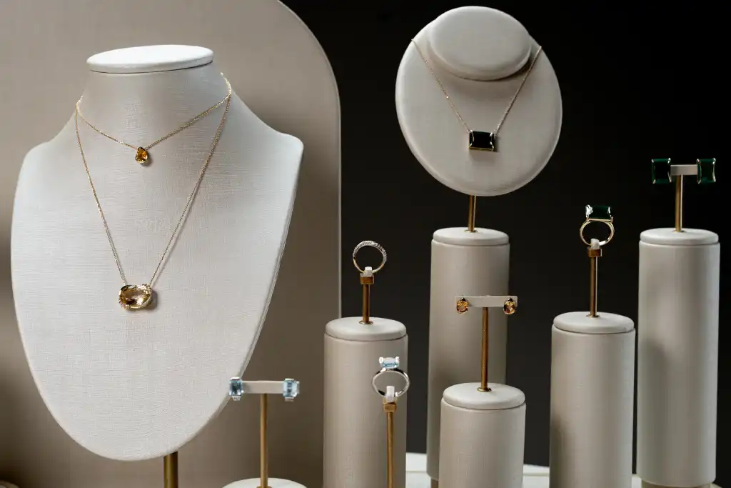 Expositor de joias com diferentes peças em destaque, incluindo colares, brincos e anéis, apresentadas de forma elegante e organizada.