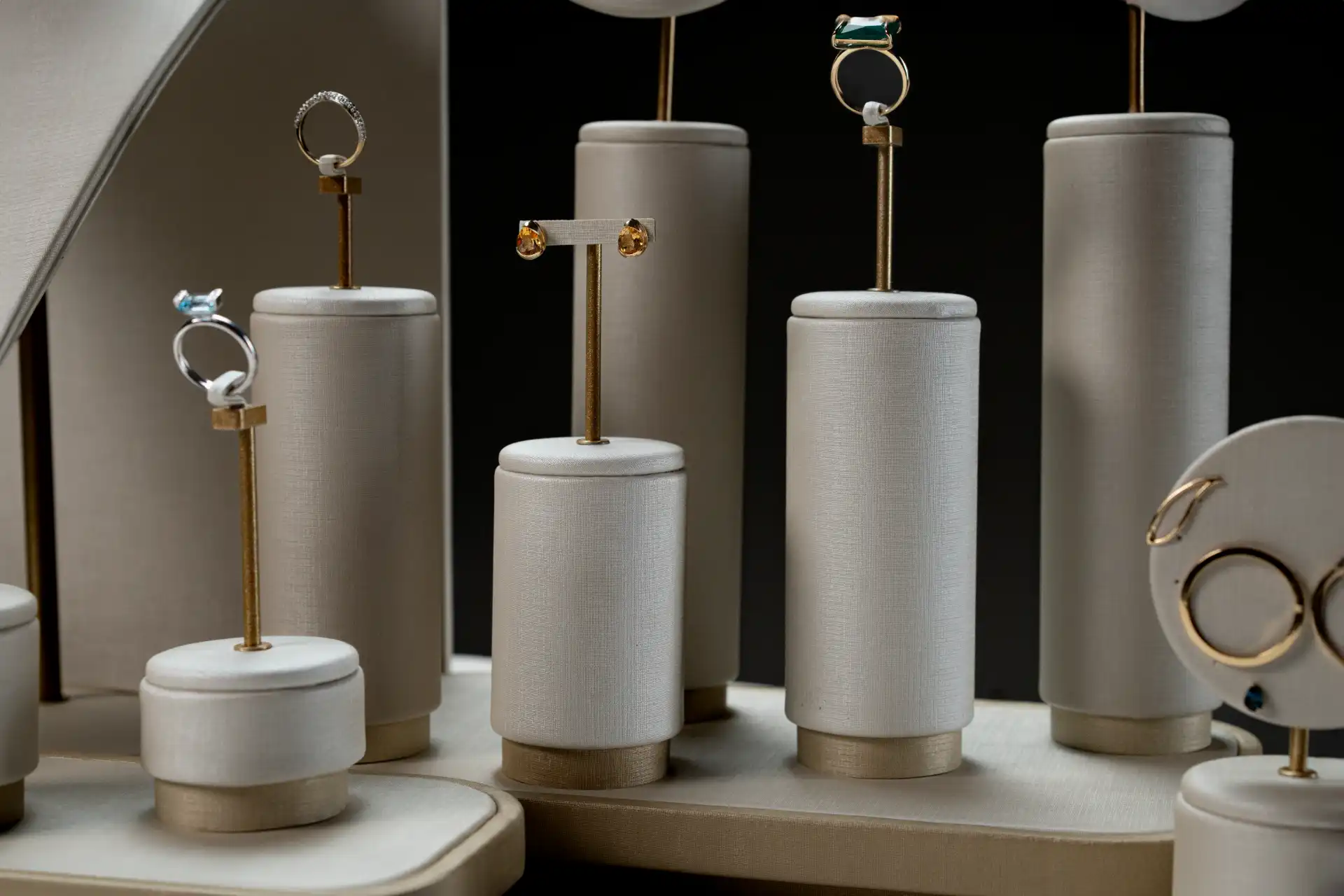 Vitrine exibindo joias de ouro com diferentes formas e tamanhos, incluindo anéis e brincos, em um ambiente elegante e sofisticado.